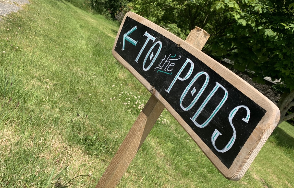 Handwritten wooden sign saying 'To the pods'