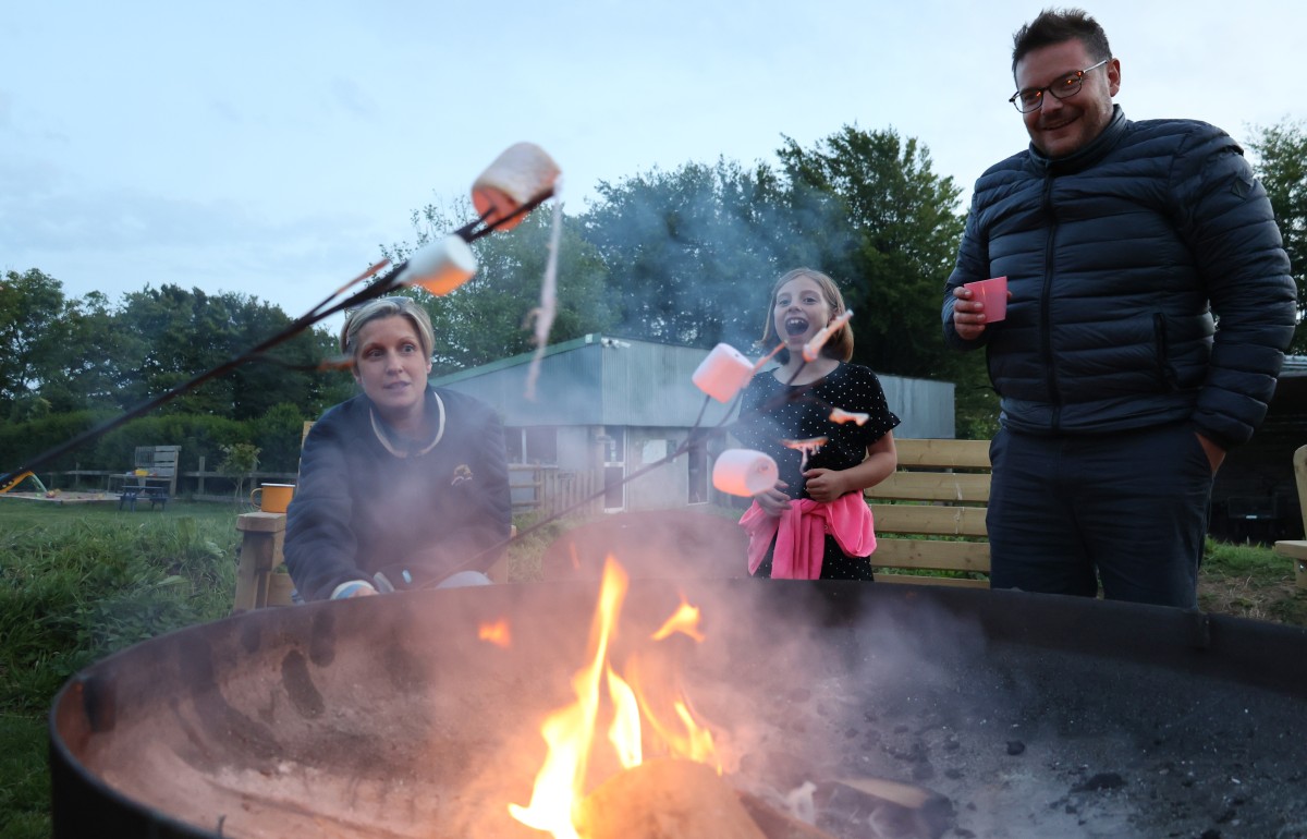 A family gather round the campfire to cook marshmallows but one has fallen into the fire!
