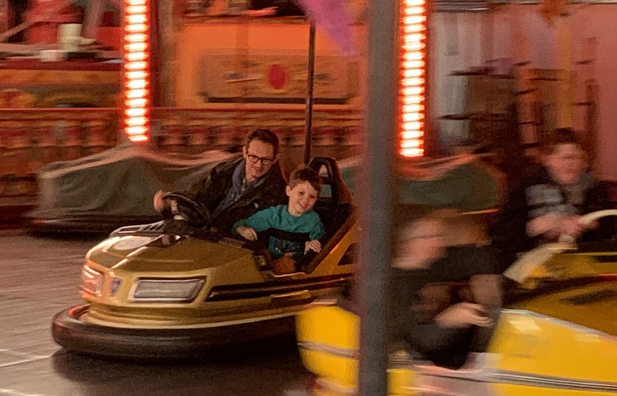 A father and son turn the corner excitedly on the dodgems